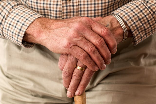 older person with their hands crossed in their lap
